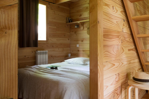 Chambre en bois avec lit à The Cabin Forest, Village Huttopia Lac de Rillé, France.
