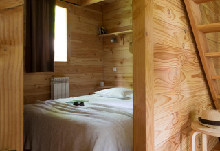 Dormitorio de madera con cama en The Cabin Forest, Village Huttopia Lac de Rillé, Francia.