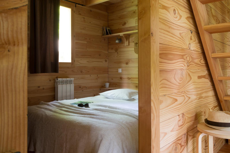 Dormitorio de madera con cama en The Cabin Forest, Village Huttopia Lac de Rillé, Francia.