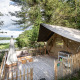 Safari telt med terrasse og udsigt til søen i naturen, Tente Trappeur Duo Village, omgivet af træer.