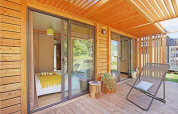Terraza de madera con silla y vista al dormitorio en Chalet Ottawa, Camping de Lyon, Francia.