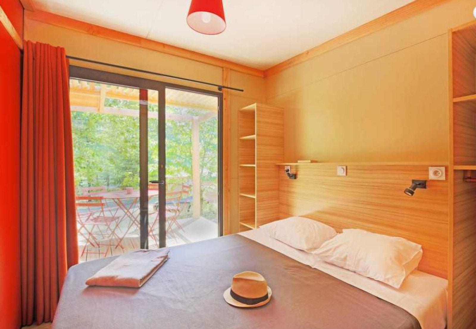 Lichte slaapkamer in Chalet Ottawa bij Camping de Lyon, Frankrijk, met tweepersoonsbed en terraszicht.