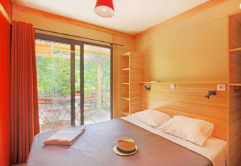 Luminoso camera da letto nel Chalet Ottawa al Camping de Lyon, Francia, con letto matrimoniale e vista terrazza.