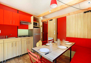 Moderne Küche und Essbereich im Chalet Ottawa, Camping de Lyon, mit roten Akzenten und Holzwänden.