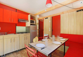 Cucina moderna e zona pranzo allo Chalet Ottawa, Camping de Lyon, con elementi rossi e legno chiaro.