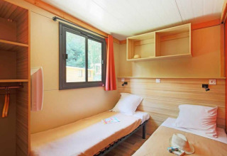 Dos camas individuales en una habitación luminosa del Chalet Ottawa, Camping de Lyon, Francia, con ventana y estantes.