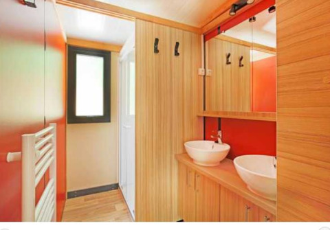 Baño moderno con dos lavabos y detalles de madera en Chalet Ottawa en Camping de Lyon, Francia.