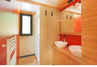 Baño moderno con dos lavabos y detalles de madera en Chalet Ottawa en Camping de Lyon, Francia.