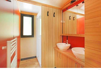 Bagno moderno con due lavandini e dettagli in legno nel Chalet Ottawa al Camping de Lyon, Francia.