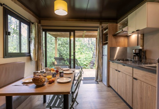 Moderne Küche und Essbereich im Chalet Ottawa auf dem Camping de Lyon mit Blick auf die Terrasse in Frankreich.