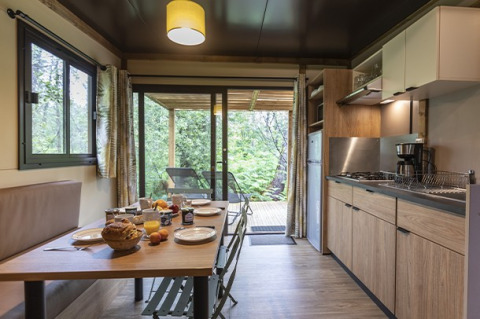 Cocina y comedor modernos en el Chalet Ottawa de Camping de Lyon, con vista a una terraza verde en Francia.