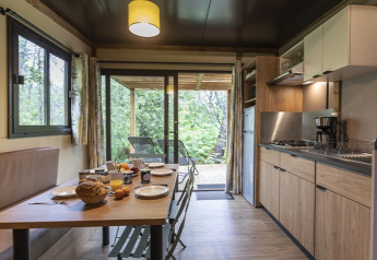 Cucina e sala da pranzo moderne nello Chalet Ottawa al Camping de Lyon, con vista terrazza verde in Francia.