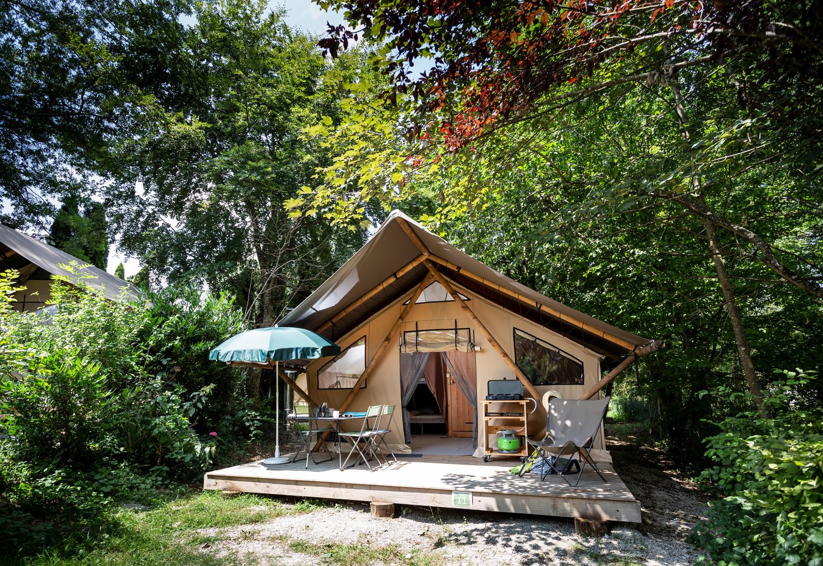 Safaritent met houten veranda en tuinmeubilair bij Huttopia Pays de Cordes sur Ciel, omringd door natuur.