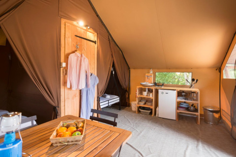 Vista interior de la tienda de safari Tent Trappeur con cocina, mesa de comedor y ambiente acogedor en Francia.