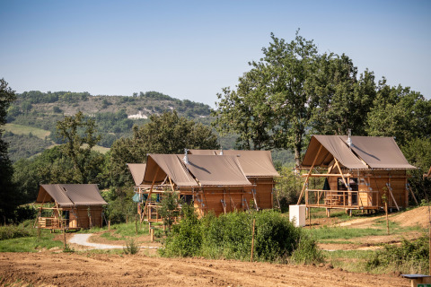 Vier Safari-Zelte namens Cahutte im Huttopia Pays de Cordes sur Ciel in Frankreich, umgeben von Natur.