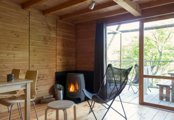 Interieur van safaritent Cahutte met houten wanden, houtkachel en terras met uitzicht op de natuur.