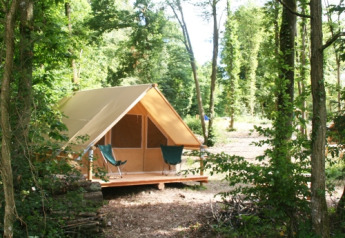 Ein Safari-Zelt namens Canadienne im Village Huttopia Senonches, Frankreich, inmitten eines Waldes.