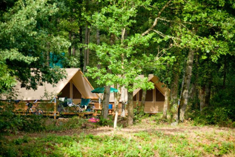 La tenda safari chiamata tenda Canadienne nei boschi di Village Huttopia Senonches in Francia, circondata da alberi.