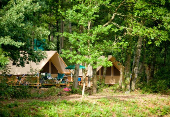 Safari-Zelt namens Canadienne-Zelt im Wald im Village Huttopia Senonches in Frankreich, umgeben von Bäumen.
