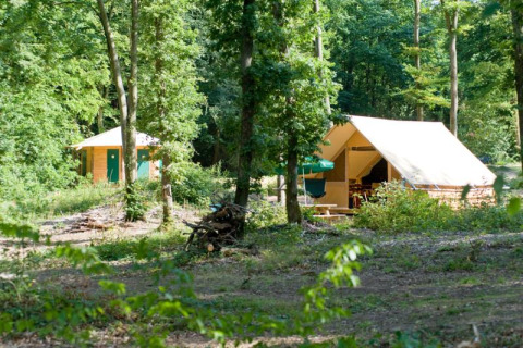 Tienda safari Canadienne en Village Huttopia Senonches, Francia, rodeada de árboles en un bosque verde.