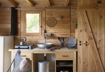 Küchenbereich im Safarizelt Cahutte im Village Huttopia Senonches in Frankreich mit Holzverkleidung.