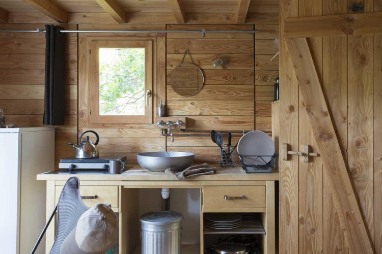 Zona de cocina en la tienda safari Cahutte en Village Huttopia Senonches, Francia, con paredes de madera.
