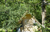 Tienda safari Canadienne en Village Huttopia Dieulefit, Francia, rodeada de árboles y vegetación abundante.