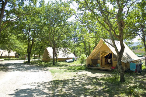 Tienda safari Canadienne en Village Huttopia Dieulefit, Francia, rodeada de árboles y paisaje verde.
