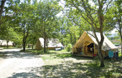 Tienda safari Canadienne en Village Huttopia Dieulefit, Francia, rodeada de árboles y paisaje verde.