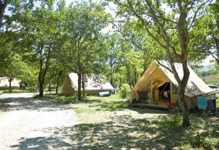 Tienda safari Canadienne en Village Huttopia Dieulefit, Francia, rodeada de árboles y paisaje verde.