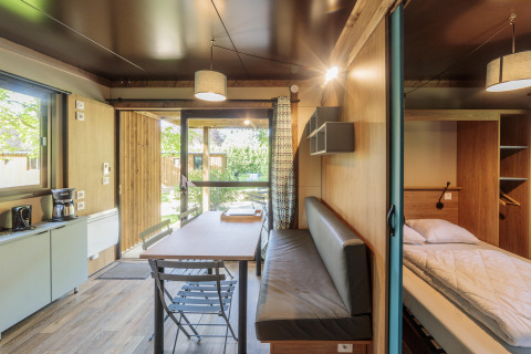 Vista interior de Chalet Evasion en Camping Valkenburg - Maastricht, con mesa, banco y cama.