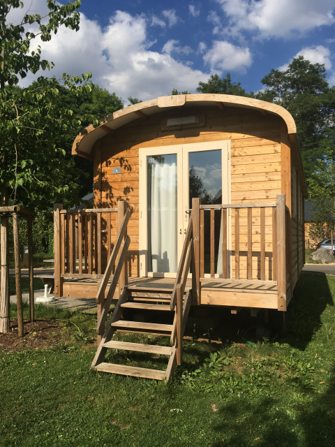 Cabaña de madera llamada Gypsy caravan en Camping Valkenburg - Maastricht en los Países Bajos, vista frontal y escalera.