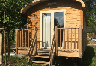 Cabaña de madera llamada Gypsy caravan en Camping Valkenburg - Maastricht en los Países Bajos, vista frontal y escalera.