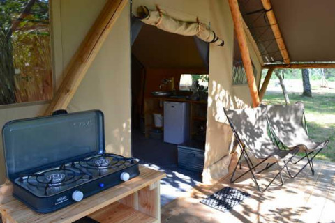 Safari-Zelt Trappeur im Huttopia De Roos, Niederlande, mit Gasherd, Campingstühlen und Waldblick.