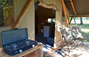 Tienda safari Trappeur en Huttopia De Roos, Países Bajos, con estufa de gas y sillas de camping afuera.
