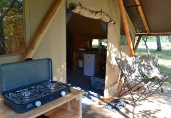 Tienda safari Trappeur en Huttopia De Roos, Países Bajos, con estufa de gas y sillas de camping afuera.