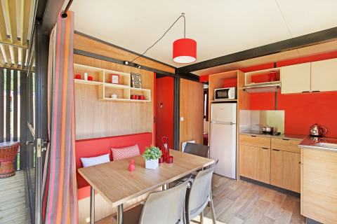 Moderne keuken en eetruimte in Chalet Evasion Vista bij Huttopia De Roos, Nederland, met rode tinten.