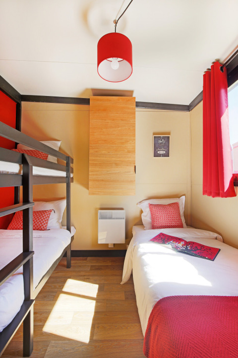 Gezellige slaapkamer met stapelbedden in Chalet Evasion Vista bij Huttopia De Roos, Nederland, rood decor.