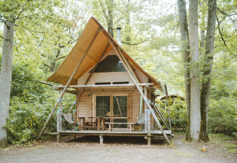 Tienda safari Cahutte en Huttopia De Roos, Países Bajos, rodeada de árboles y naturaleza verde.