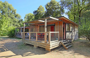 Houten chalet bij Chalet Toronto in Huttopia De Roos, Nederland, met terras en omringd door bomen.