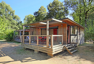 Cabaña de madera en Chalet Toronto, Huttopia De Roos, Países Bajos, rodeada de árboles y naturaleza.
