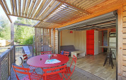 Vista interior y exterior del Chalet Toronto en Huttopia De Roos, Países Bajos, con mesa roja de comedor.