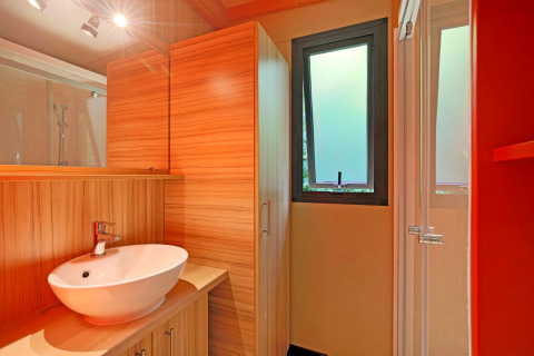 Modernes Badezimmer mit Holzoberflächen, Waschtisch und Frostfenster im Chalet Toronto, Huttopia De Roos, Niederlande.