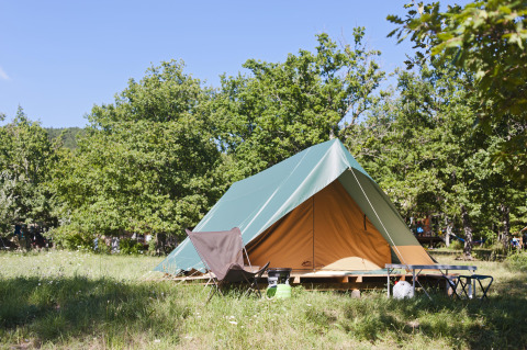 Een tipi-tent genaamd Tent Bonaventure in Village Huttopia Lanmary in Frankrijk, tussen de groene bomen.