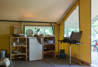 Küche im Safarizelt Trappeur Zelt I im Village Huttopia Lanmary, Frankreich, mit Kochstelle und Kühlschrank.