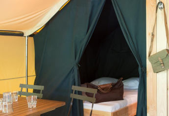 Indvendigt billede af Trappeur-teltet I ved Village Huttopia Lanmary i Frankrig med senge og siddeområde.