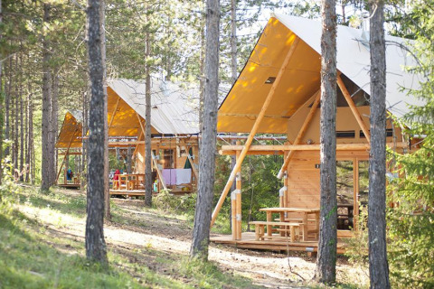Tiendas safari Cahutte en Village Huttopia Lanmary, Francia, rodeadas de bosque para glamping natural.