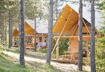 Tiendas safari Cahutte en Village Huttopia Lanmary, Francia, rodeadas de bosque para glamping natural.