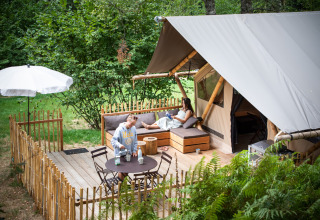Twee personen genieten buiten een Trappeur Safari Tent bij Village Huttopia Pays de Condrieu in Frankrijk.