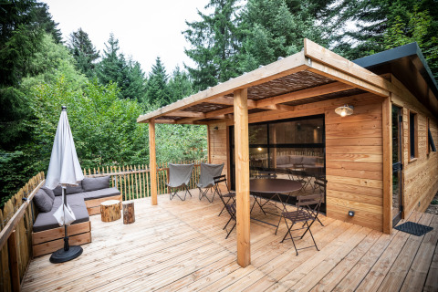 Terraza de madera en Chalet Toronto con asientos, sombrilla y rodeada de exuberantes árboles verdes.